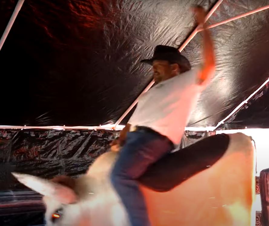Man riding Fu Manchu the mechanical bull, falling backward