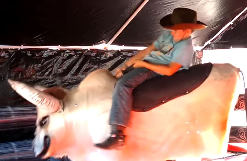 Boy riding Fu Manchu the mechanical bull under the tent